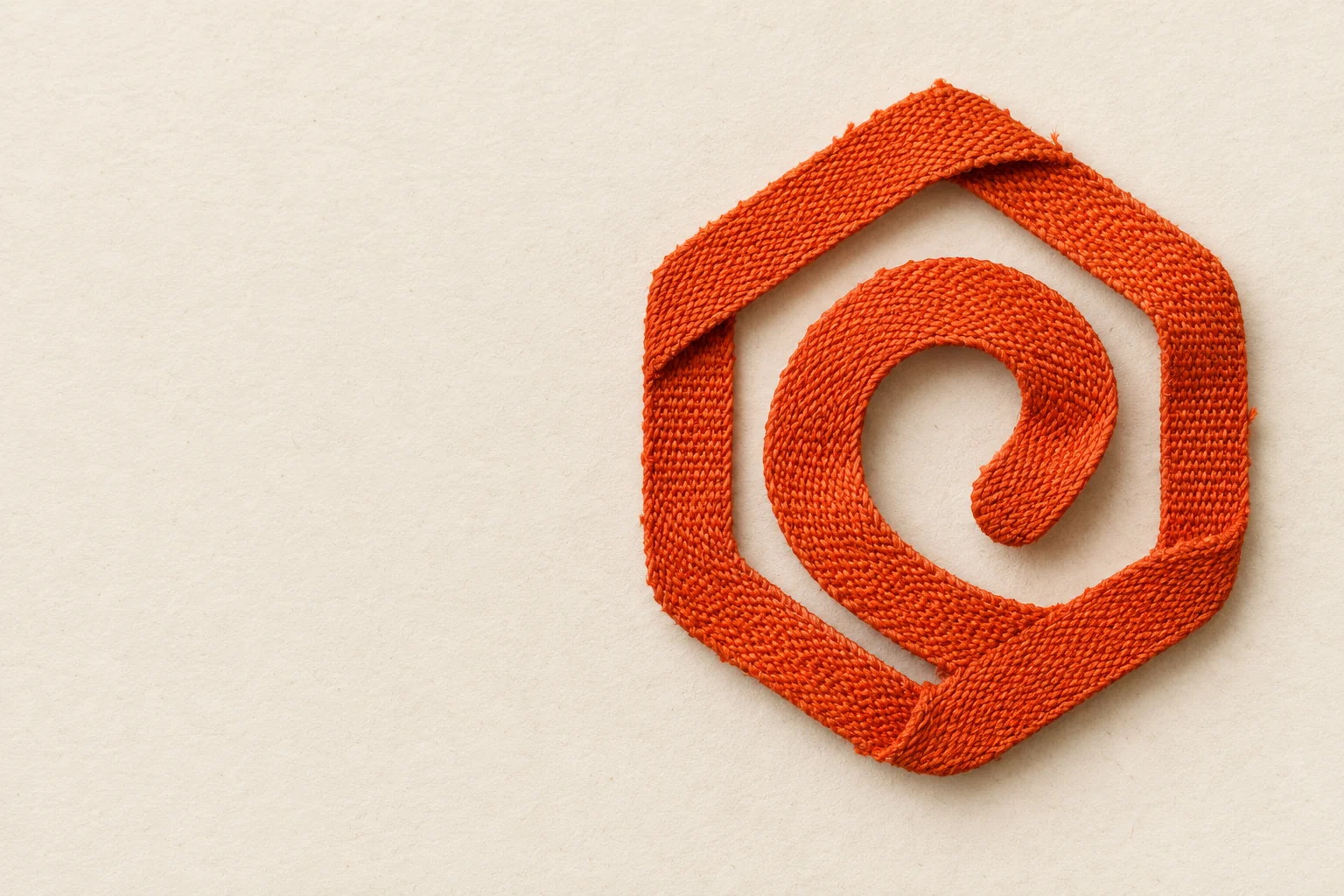 The Obelo mark formed from a continuous orange woven ribbon